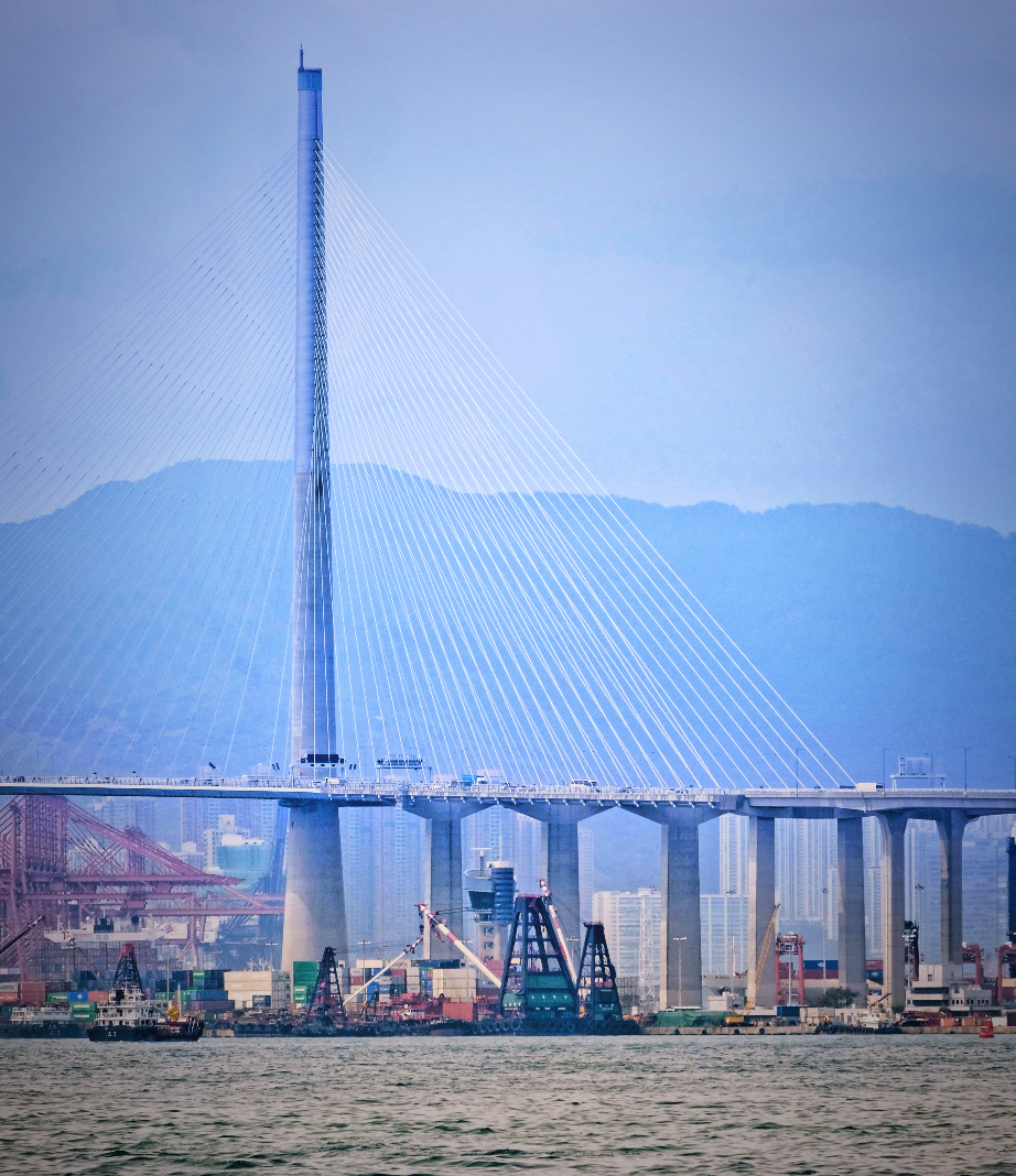 A powerful real-world shot of a Hong Kong cable-stayed bridge and busy container port, connecting science to global trade